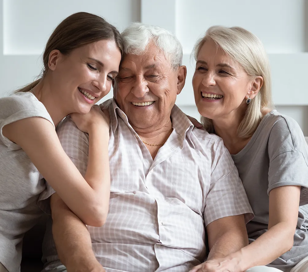 daughter smiling and hugging senior parents